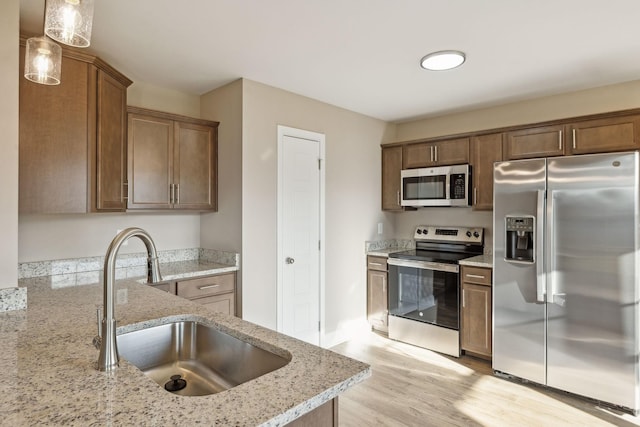 1271 Racker Dr, Clarksville, TN 37043 - kitchen featuring appliances with stainless steel finishes, a sink, light wood finished floors, light stone counters, and pendant lighting