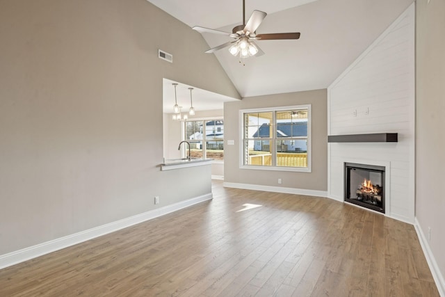1271 Racker Dr, Clarksville, TN 37043 - unfurnished living room with a fireplace, a ceiling fan, baseboards, wood finished floors, and high vaulted ceiling