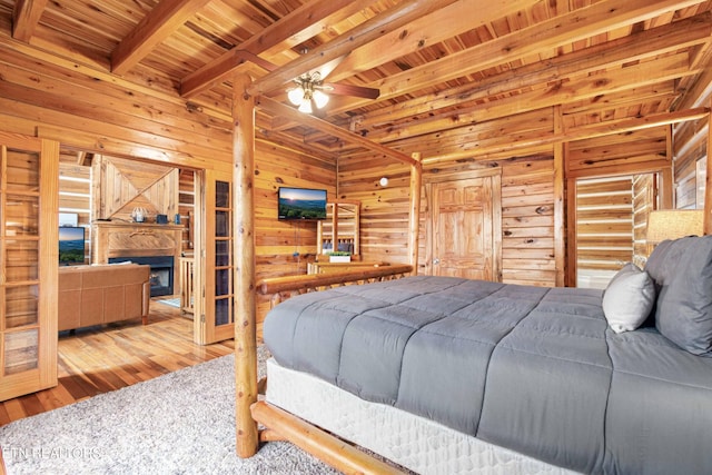 1815 Silver Poplar Ln, Sevierville, TN 37876 - bedroom with wooden ceiling with exposed beams, wood-type flooring, wood walls, and a fireplace