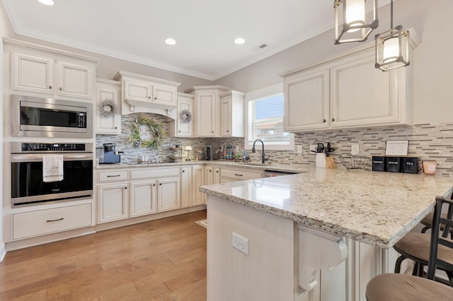 1114 Escalade Ct, Lascassas, TN 37085 - kitchen featuring stainless steel appliances, a sink, a peninsula, a breakfast bar, and light wood-type flooring