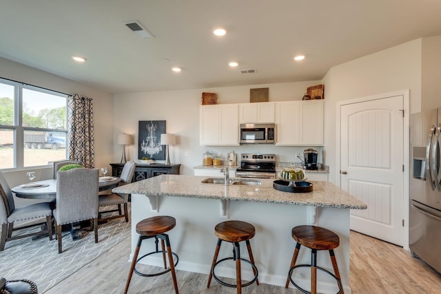 4922 Mowbray Way, Murfreesboro, TN 37129 - kitchen with stainless steel appliances, light wood-type flooring, a breakfast bar, white cabinetry, and light stone countertops