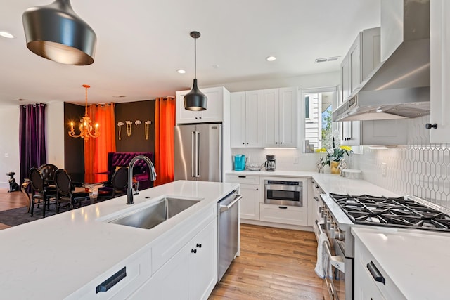 1203B Brick Church Pike, Nashville, TN 37207 - kitchen with high end appliances, a sink, wall chimney exhaust hood, a chandelier, and light wood-style flooring