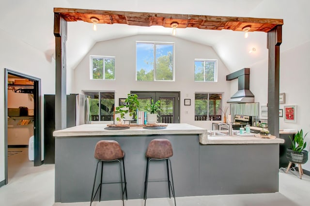 6969 Cuba Landing Rd, Waverly, TN 37185 - kitchen with wall chimney exhaust hood, high vaulted ceiling, concrete floors, light countertops, and a breakfast bar