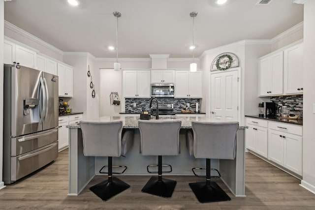 4537 Rockland Trl, Antioch, TN 37013 - kitchen featuring stainless steel appliances, tasteful backsplash, white cabinets, ornamental molding, and a center island with sink