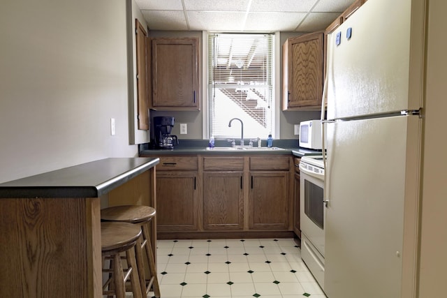 535 Dawson Rd, Cumberland Furnace, TN 37051 - kitchen featuring white appliances, dark countertops, a paneled ceiling, and brown cabinetry