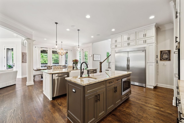 1234 Saddle Springs Dr, Thompsons Station, TN 37179 - kitchen with built in appliances, a kitchen island with sink, ornate columns, ornamental molding, and recessed lighting