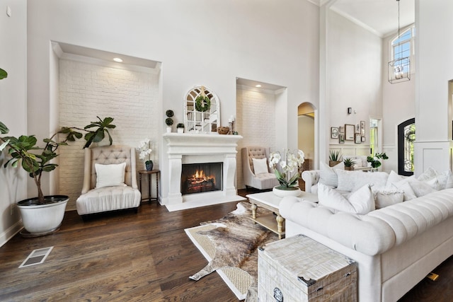 1234 Saddle Springs Dr, Thompsons Station, TN 37179 - living area featuring arched walkways, a towering ceiling, wood finished floors, a lit fireplace, and ornamental molding