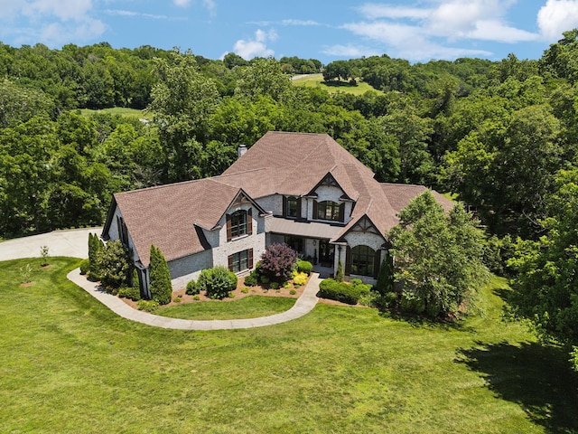 1234 Saddle Springs Dr, Thompsons Station, TN 37179 - view of front of home featuring a balcony, a front yard, stone siding, and a forest view