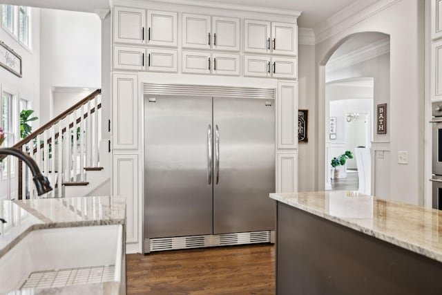 1234 Saddle Springs Dr, Thompsons Station, TN 37179 - kitchen featuring appliances with stainless steel finishes, ornamental molding, a sink, arched walkways, and white cabinets