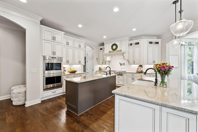1234 Saddle Springs Dr, Thompsons Station, TN 37179 - kitchen featuring stainless steel appliances, arched walkways, crown molding, backsplash, and an island with sink