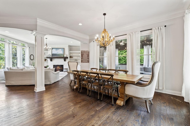 1234 Saddle Springs Dr, Thompsons Station, TN 37179 - dining space featuring arched walkways, a lit fireplace, a chandelier, dark wood-type flooring, and crown molding