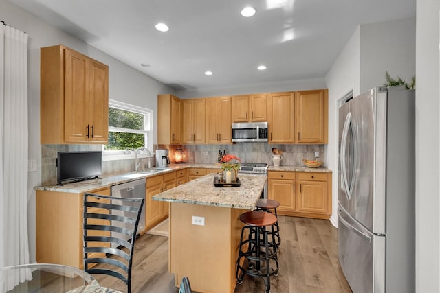 1154 Olde Cameron Ln, Franklin, TN 37067 - kitchen with stainless steel appliances, a sink, a center island, light wood-style flooring, and decorative backsplash