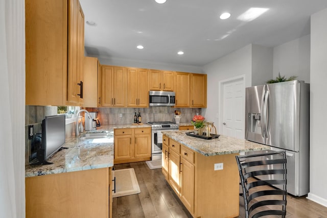 1154 Olde Cameron Ln, Franklin, TN 37067 - kitchen featuring appliances with stainless steel finishes, a sink, a center island, wood finished floors, and light stone counters