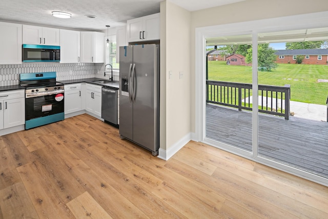 316 Bybee Branch Rd, Mcminnville, TN 37110 - kitchen with appliances with stainless steel finishes, dark countertops, a sink, backsplash, and white cabinetry
