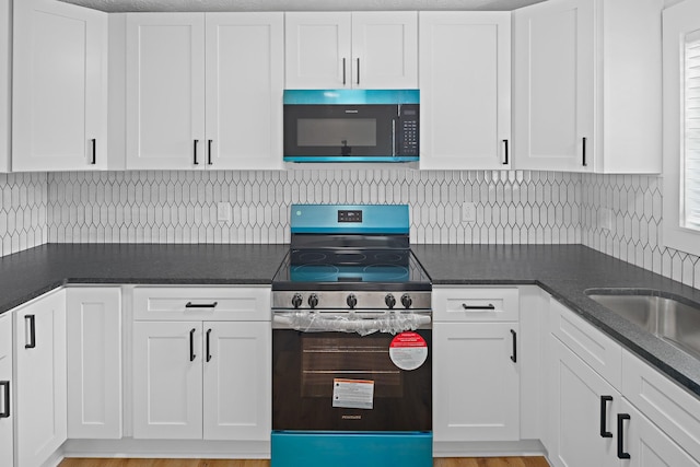 316 Bybee Branch Rd, Mcminnville, TN 37110 - kitchen with black microwave, electric stove, white cabinetry, and backsplash