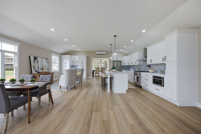 5935 S New Hope Rd, Hermitage, TN 37076 - kitchen with appliances with stainless steel finishes, lofted ceiling, wall chimney exhaust hood, a breakfast bar area, and light wood-type flooring