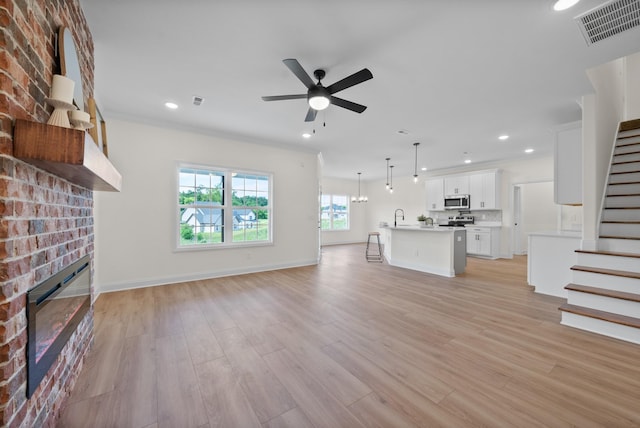 583 Pongracz Way, Clarksville, TN 37042 - unfurnished living room featuring a fireplace, stairway, ceiling fan, light wood finished floors, and recessed lighting