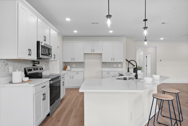 583 Pongracz Way, Clarksville, TN 37042 - kitchen with appliances with stainless steel finishes, a sink, white cabinetry, light wood-style flooring, and decorative light fixtures