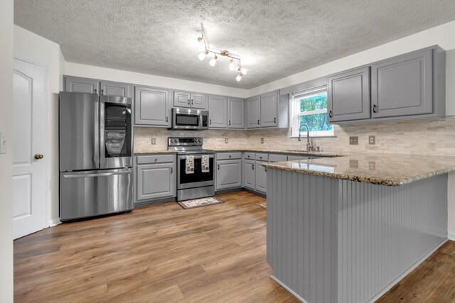 3471 Esquire Dr, Murfreesboro, TN 37130 - kitchen with stainless steel appliances, gray cabinetry, a peninsula, light wood-style floors, and a sink