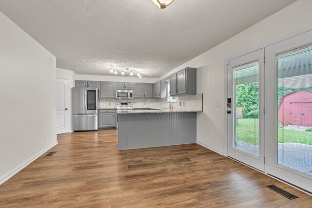 3471 Esquire Dr, Murfreesboro, TN 37130 - kitchen with gray cabinets, stainless steel appliances, a peninsula, backsplash, and dark wood-style flooring