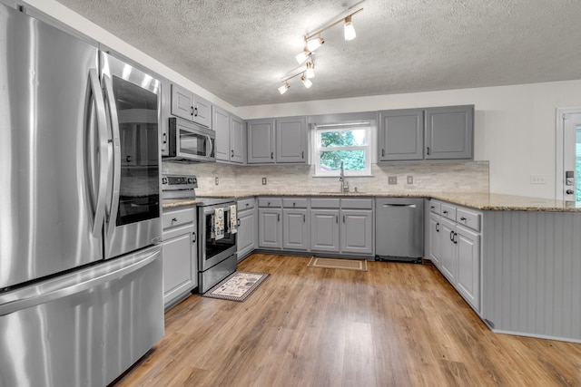 3471 Esquire Dr, Murfreesboro, TN 37130 - kitchen with stainless steel appliances, gray cabinetry, a sink, a textured ceiling, and light wood-style flooring