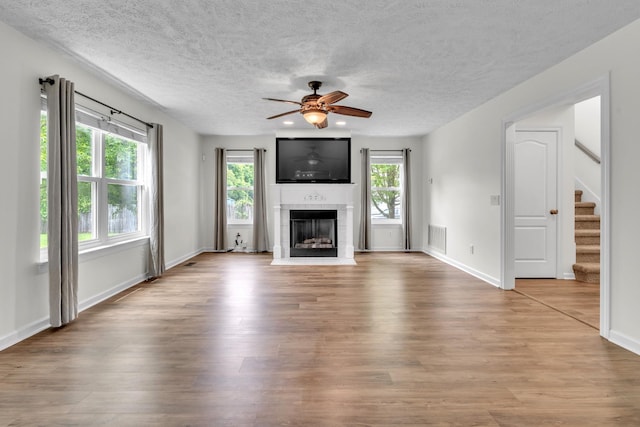 3471 Esquire Dr, Murfreesboro, TN 37130 - unfurnished living room with ceiling fan, wood finished floors, a fireplace with flush hearth, stairs, and a textured ceiling