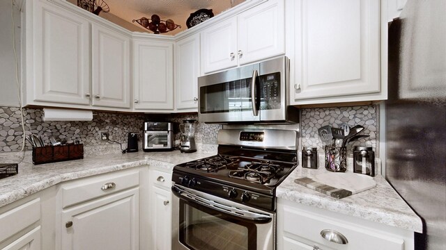 813 Chaney Woods Dr, La Vergne, TN 37086 - kitchen featuring stainless steel appliances, white cabinetry, light countertops, and backsplash