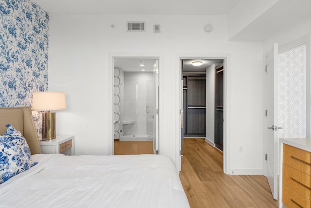1212 Laurel St Unit 2005, Nashville, TN 37203 - bedroom featuring light wood-type flooring, a spacious closet, connected bathroom, a closet, and baseboards