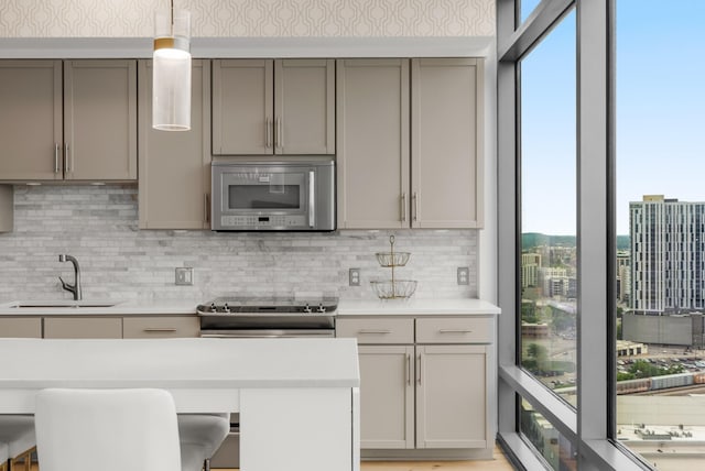 1212 Laurel St Unit 2005, Nashville, TN 37203 - kitchen with appliances with stainless steel finishes, a sink, gray cabinetry, wallpapered walls, and healthy amount of natural light