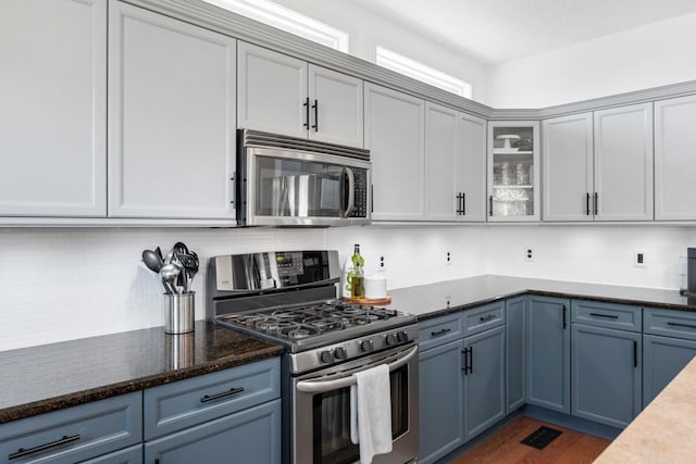1300 Wentworth Dr, Gallatin, TN 37066 - kitchen featuring stainless steel appliances, glass insert cabinets, dark wood-style floors, dark stone countertops, and blue cabinets