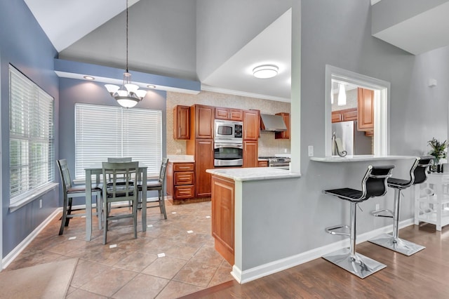 1838 Oreilly Cir, Spring Hill, TN 37174 - kitchen featuring appliances with stainless steel finishes, wall chimney exhaust hood, brown cabinets, light countertops, and baseboards