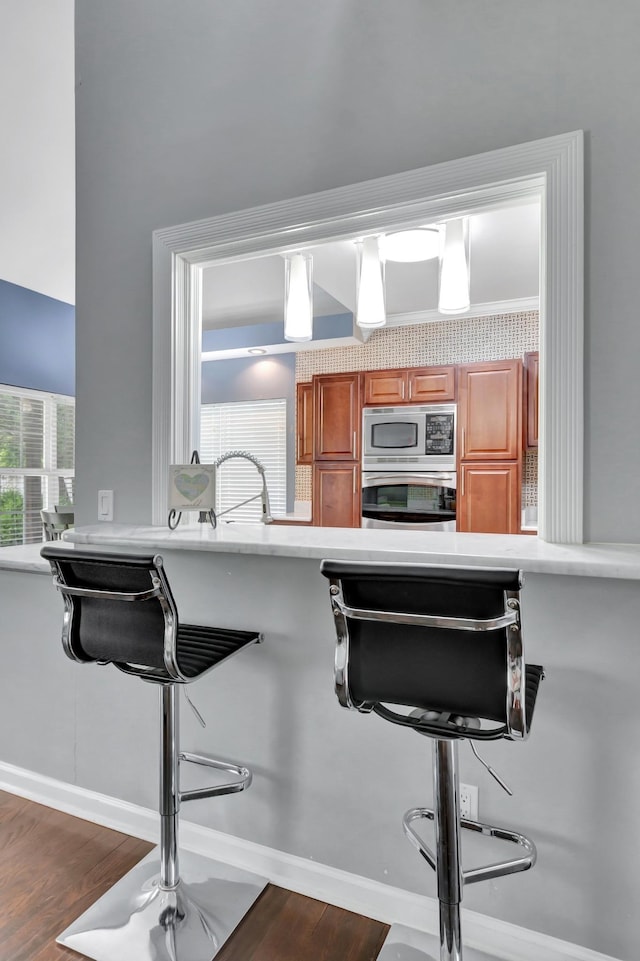 1838 Oreilly Cir, Spring Hill, TN 37174 - kitchen with appliances with stainless steel finishes, dark wood-style floors, brown cabinetry, a breakfast bar, and light countertops
