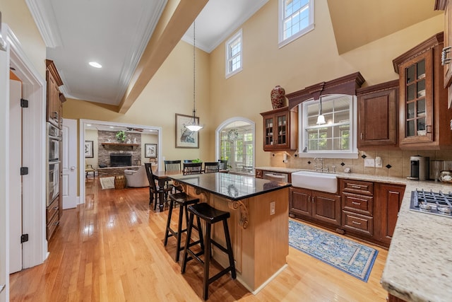 15687 Columbia Hwy, Lynnville, TN 38472 - kitchen featuring a sink, light wood-style floors, a kitchen bar, a stone fireplace, and a kitchen island