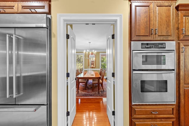 15687 Columbia Hwy, Lynnville, TN 38472 - kitchen with stainless steel appliances, light wood finished floors, a chandelier, and brown cabinets