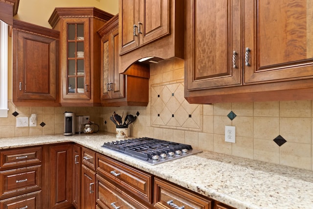 15687 Columbia Hwy, Lynnville, TN 38472 - kitchen with stainless steel gas cooktop, tasteful backsplash, glass insert cabinets, and brown cabinetry
