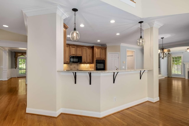 3037 Flagstone Dr, Franklin, TN 37069 - kitchen featuring black appliances, brown cabinetry, a kitchen bar, a chandelier, and crown molding