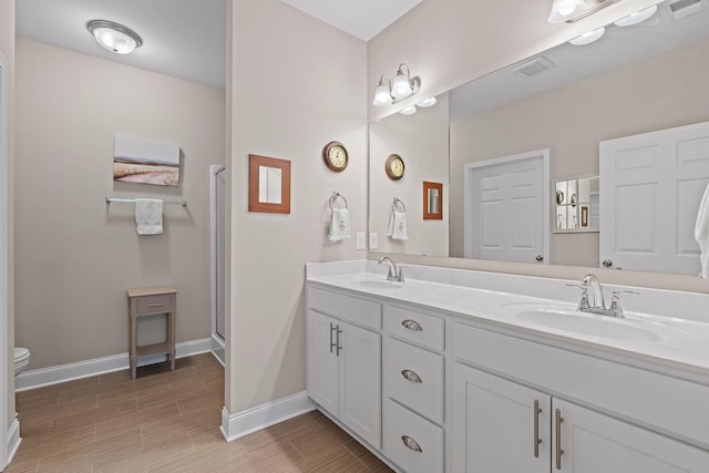 1648 Foston Ln, Gallatin, TN 37066 - bathroom with toilet, double vanity, baseboards, wood finish floors, and a shower with shower door