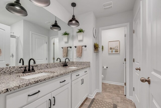 803 Dallas Dr, Columbia, TN 38401 - bathroom with double vanity, toilet, a shower stall, baseboards, and stone finish flooring