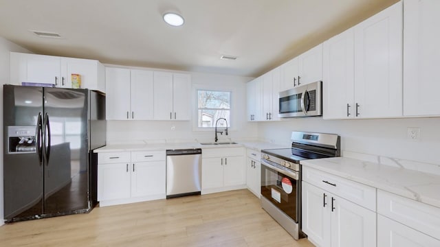 121 Highland St, La Vergne, TN 37086 - kitchen featuring appliances with stainless steel finishes, a sink, light wood finished floors, light stone counters, and white cabinets
