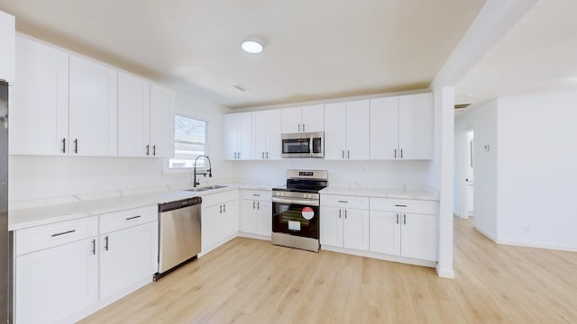 121 Highland St, La Vergne, TN 37086 - kitchen with appliances with stainless steel finishes, a sink, light wood-style floors, white cabinets, and light stone countertops
