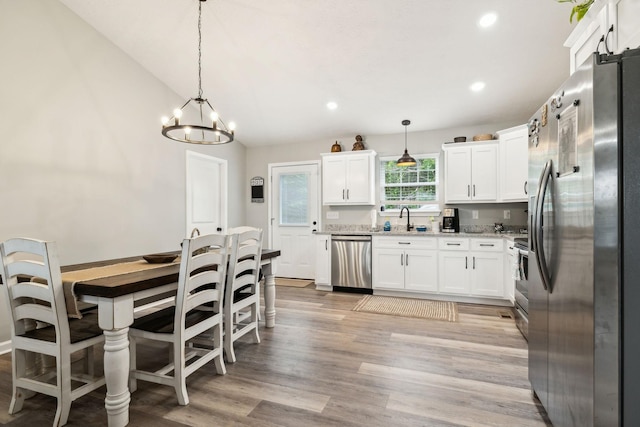 125 Vivian Ln, Carthage, TN 37030 - kitchen featuring appliances with stainless steel finishes, a chandelier, white cabinets, light stone countertops, and light wood-style flooring