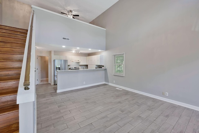 4905 Algonquin Trl, Antioch, TN 37013 - unfurnished living room featuring a ceiling fan, baseboards, high vaulted ceiling, stairs, and light wood finished floors