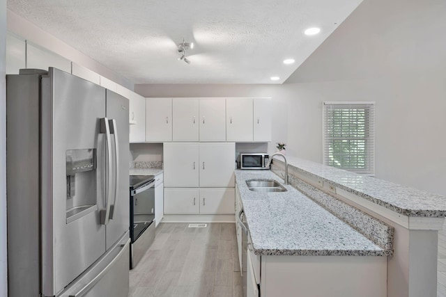 4905 Algonquin Trl, Antioch, TN 37013 - kitchen featuring appliances with stainless steel finishes, a sink, a peninsula, a textured ceiling, and light wood-type flooring