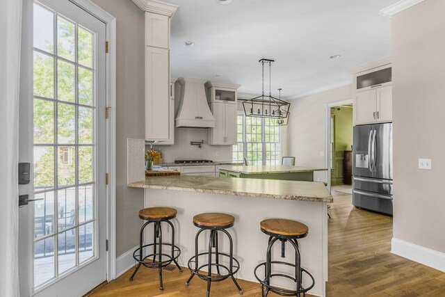1422 Primrose Ln, Franklin, TN 37064 - kitchen featuring stainless steel appliances, custom exhaust hood, a peninsula, backsplash, and a kitchen breakfast bar