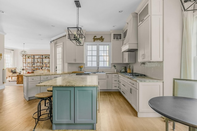 1422 Primrose Ln, Franklin, TN 37064 - kitchen with custom exhaust hood, a peninsula, a sink, a chandelier, and stainless steel gas cooktop