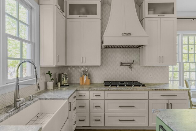 1422 Primrose Ln, Franklin, TN 37064 - kitchen featuring a sink, custom range hood, decorative backsplash, white cabinetry, and light stone countertops