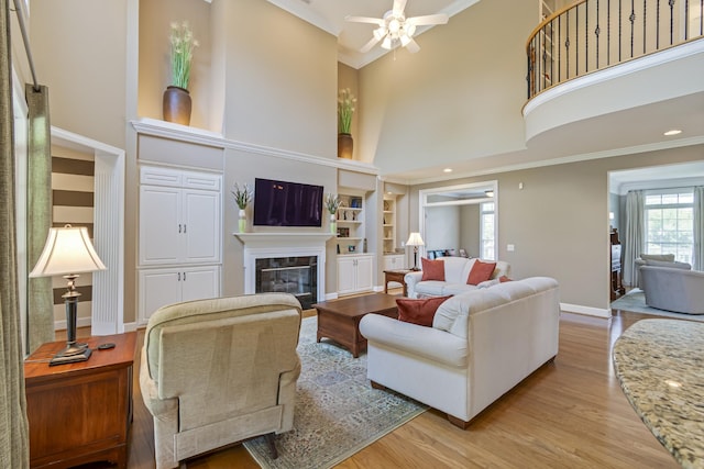 9166 Sydney Ln, Brentwood, TN 37027 - living area featuring light wood-style flooring, a glass covered fireplace, a towering ceiling, built in features, and baseboards