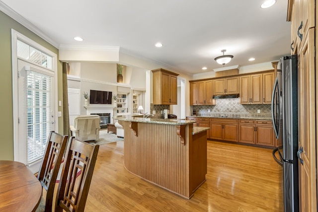 9166 Sydney Ln, Brentwood, TN 37027 - kitchen featuring a breakfast bar, crown molding, light stone countertops, freestanding refrigerator, and light wood-type flooring