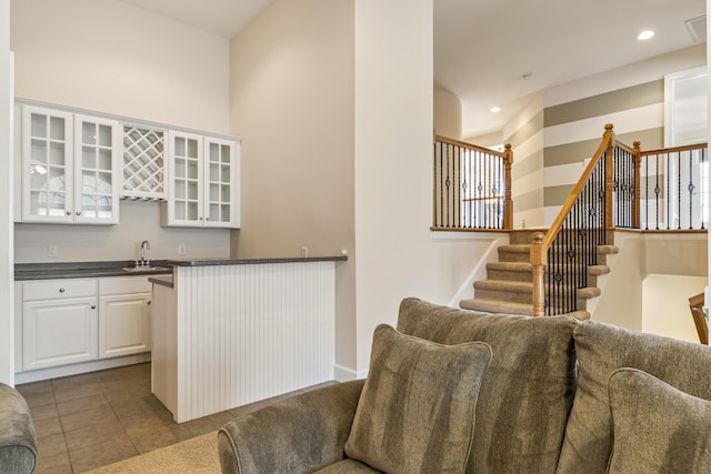9166 Sydney Ln, Brentwood, TN 37027 - kitchen with a sink, dark countertops, glass insert cabinets, white cabinets, and open floor plan
