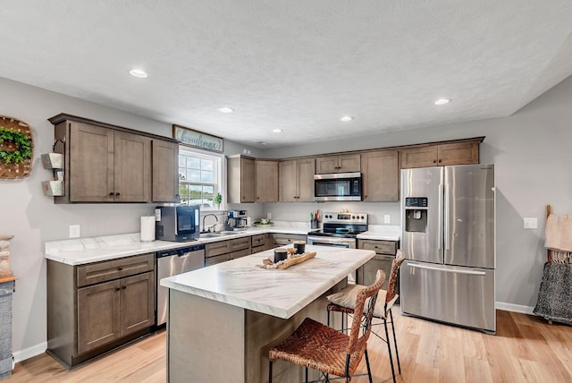 241 Holly Grove Rd, Lewisburg, TN 37091 - kitchen with appliances with stainless steel finishes, a sink, light wood-type flooring, a kitchen breakfast bar, and light countertops